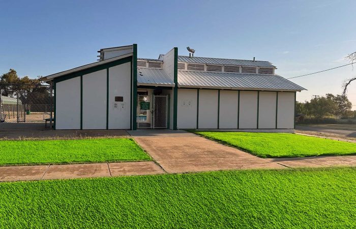 Entrance to Shamrock City Pool with green lawn and clear sky.