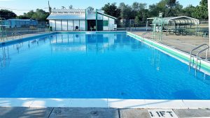 Shamrock City Pool with clear blue water, diving boards, and shaded seating area.