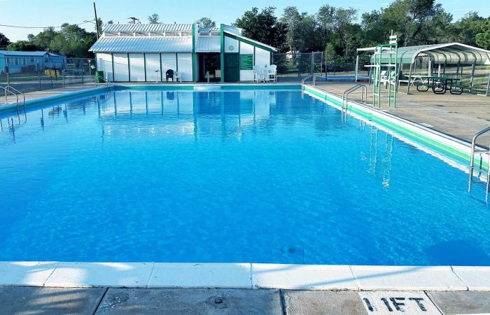 Shamrock City Pool with clear blue water, diving boards, and shaded seating area.